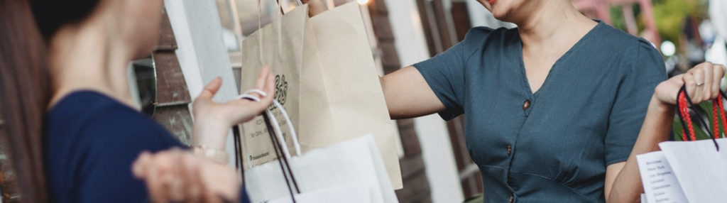 vendedor entregando pedido para cliente em sacolas de papel