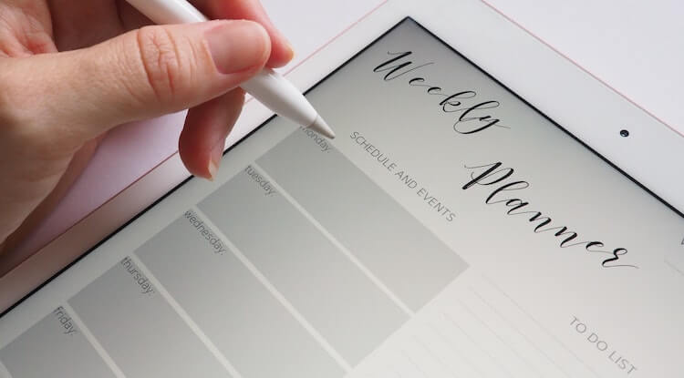Uma mão segurando uma caneta digital  prestes a escrever em um ipad.