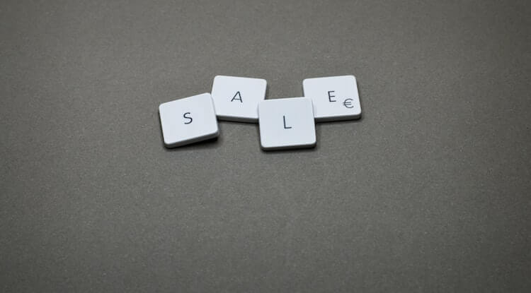 três peças quadradas pequenas enfileiradas com letras no meio. A ordem das peças formam a palavra "Sale (vendas em português)"